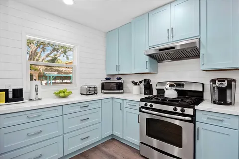 a kitchen with granite countertop white cabinets stainless steel appliances and a window