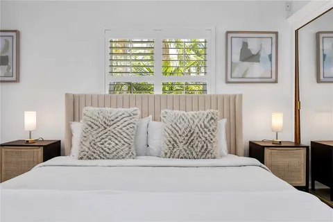 a large white bed sitting in a bedroom next to a window