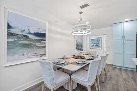a dining room with wooden floor a chandelier a wooden table and chairs
