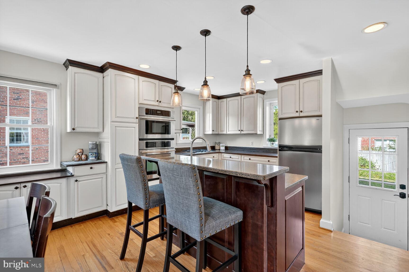 10406 Ewell Avenue Kensington, MD 20895 - Photo 18 of 42 a kitchen with stainless steel appliances granite countertop a kitchen island a stove a refrigerator with a dining table and chairs