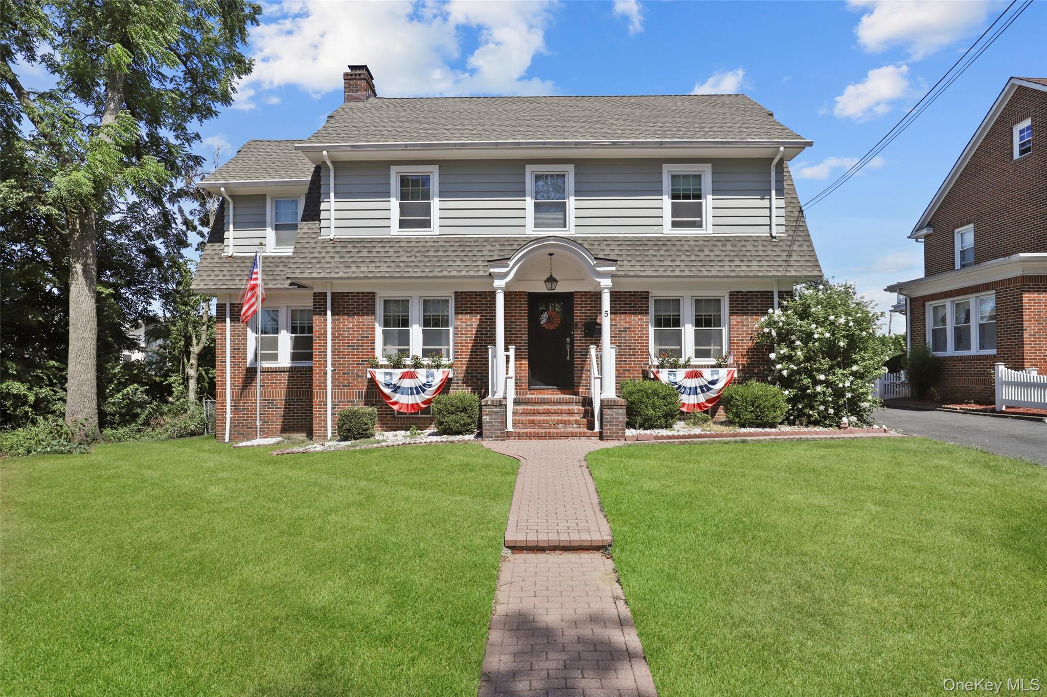 View of front of house featuring a front yard, a chimney, a shingled roof, and brick siding
