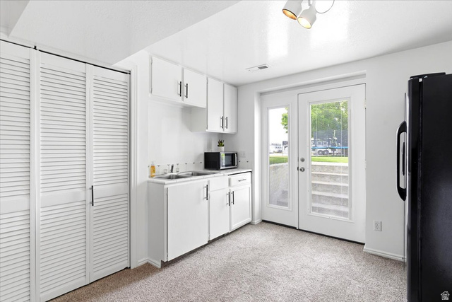 5321 South 3100th Street West Roy, UT 84067 - Photo 48 of 64 Compact kitchen space featuring white cabinetry, a double basin sink, and a black refrigerator