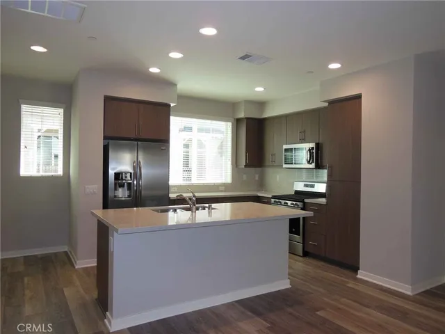 a view of a kitchen counter top space a sink wooden floor and a window
