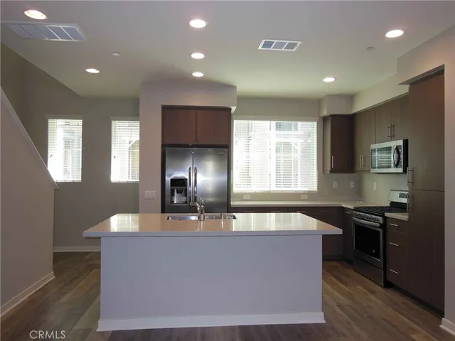 a large kitchen with granite countertop a sink a counter top space and stainless steel appliances