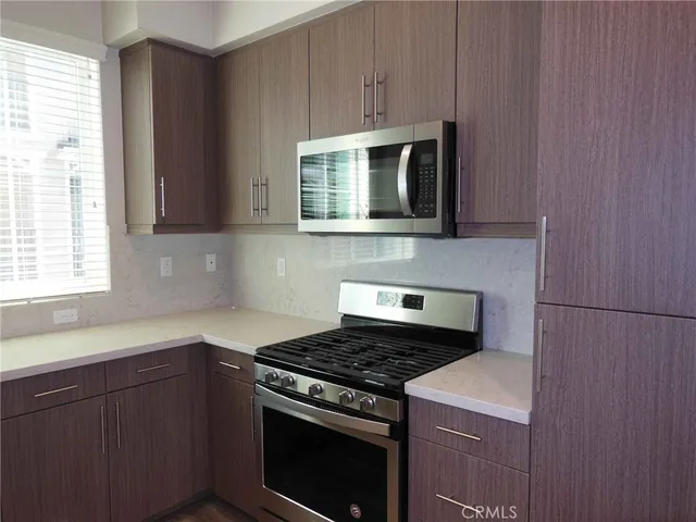 a kitchen with granite countertop cabinets stove top oven and microwave