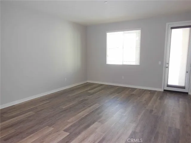 an empty room with wooden floor and window
