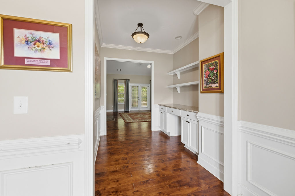 214 Friend Street Anderson, SC 29621 - Photo 3 of 40 This interior hallway features warm hardwood floors and wainscoting, leading to a light-filled living area.