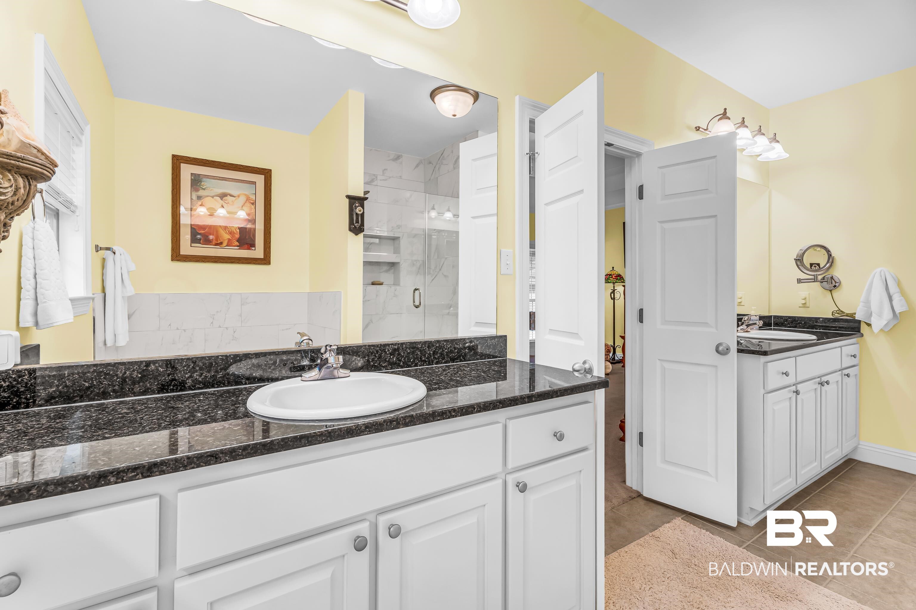 7014 Blakeley Road Daphne, AL 36527 - Photo 37 of 45 Bathroom featuring dual vanities with dark countertops, white cabinetry, and undermount sinks