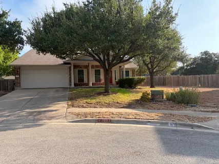 a view of a house with a large tree and wooden fence