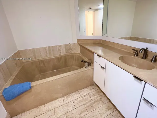 a bathroom with a granite countertop sink and a bathtub