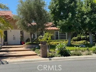 a view of a house with potted plants and large trees