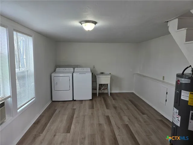 a utility room with wooden floor washer and dryer