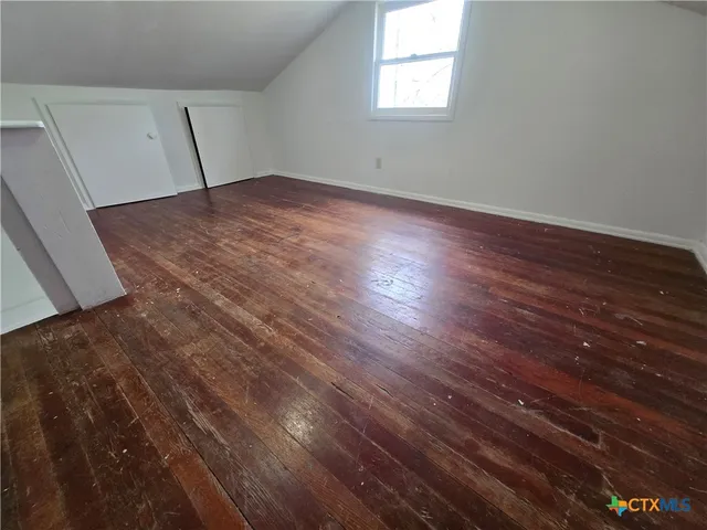 an empty room with wooden floor and window
