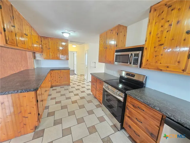 a kitchen with stainless steel appliances granite countertop a stove a sink and a microwave