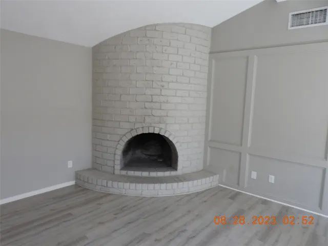 a view of an empty room with a fireplace and a window