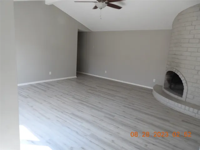 a view of an empty room with wooden floor and a fireplace