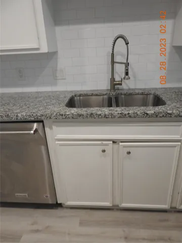 a close view of a faucet a sink and a dishwasher with wooden floor