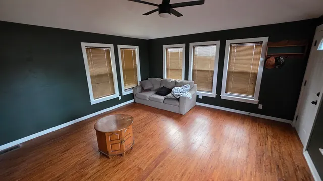 a living room with couch wooden floor and a large window