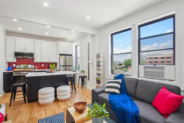 a living room with furniture kitchen and a large window