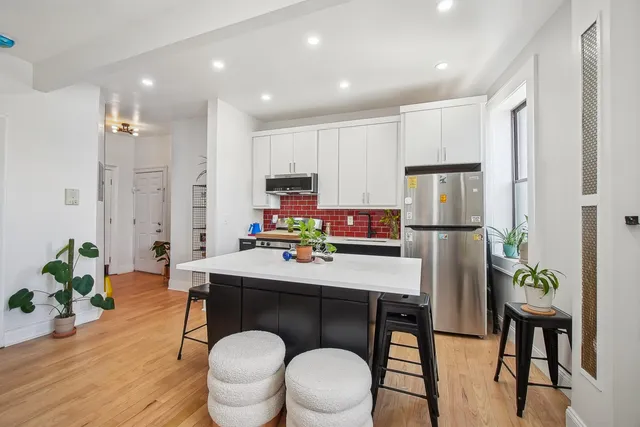 a work room with stainless steel appliances a dining table chairs and refrigerator