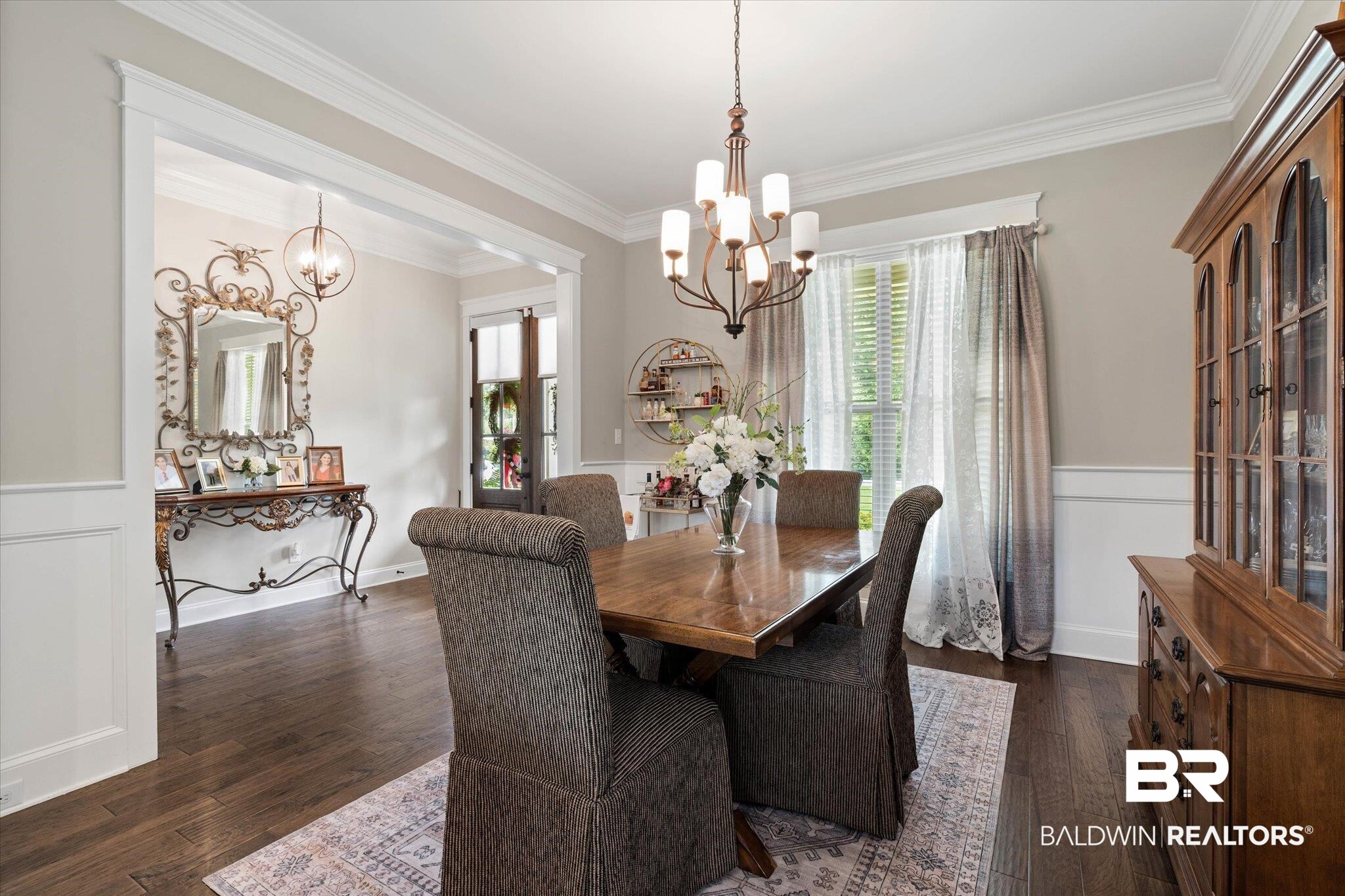 24821 Austin Road Daphne, AL 36526 - Photo 2 of 24 Dining room with a chandelier, crown molding, dark wood finished floors, and wainscoting