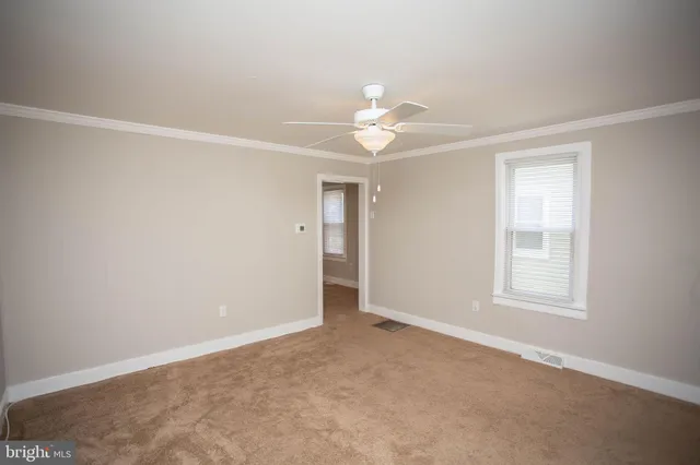 an empty room with chandelier fan and windows