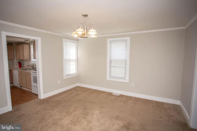 an empty room with chandelier and windows