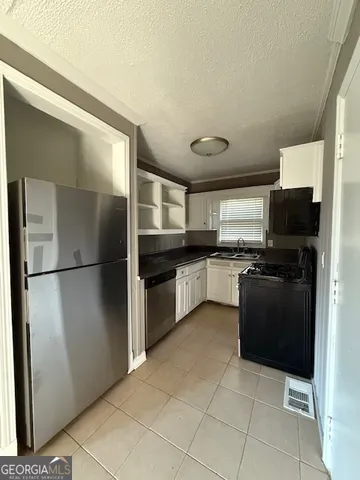 a kitchen with granite countertop a refrigerator and a stove top oven