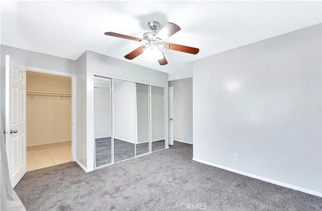 an empty room with closet and a ceiling fan