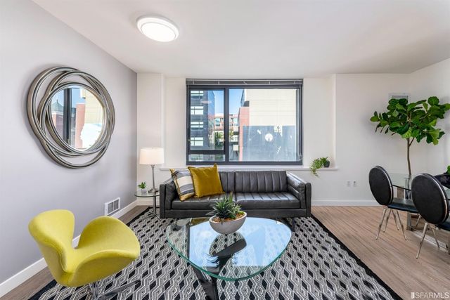 a living room with furniture a mirror and a wooden floor