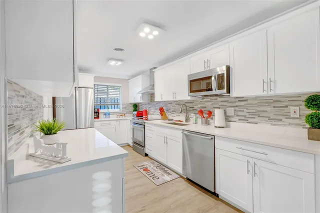 a kitchen with granite countertop a sink stainless steel appliances and white cabinets