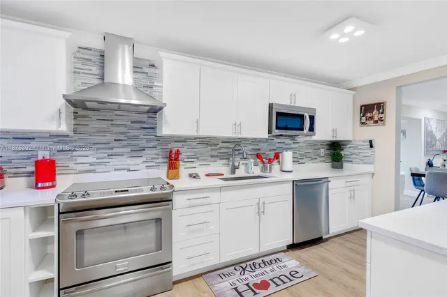 a kitchen with stainless steel appliances granite countertop a sink stove and cabinets