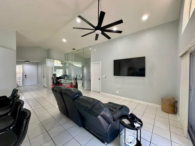 a living room with furniture a flat screen tv and a ceiling fan