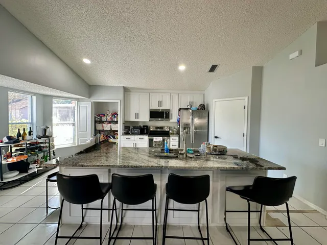 a kitchen with a dining table chairs and refrigerator