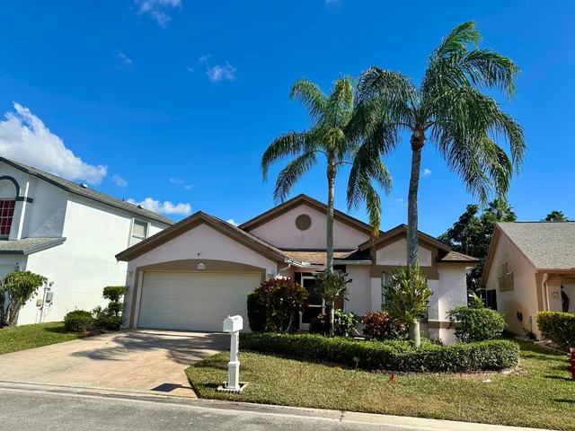 a front view of a house with a yard and potted plants