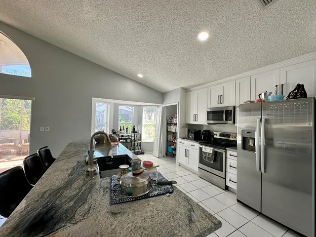 a living room with stainless steel appliances furniture a flat screen tv and a window