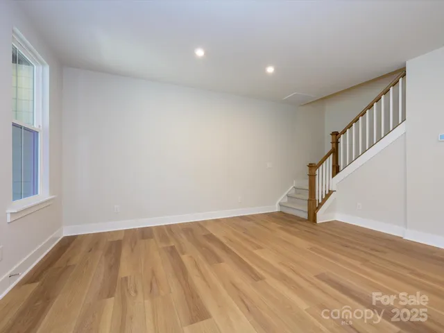 a view of an empty room with wooden floor and stairs