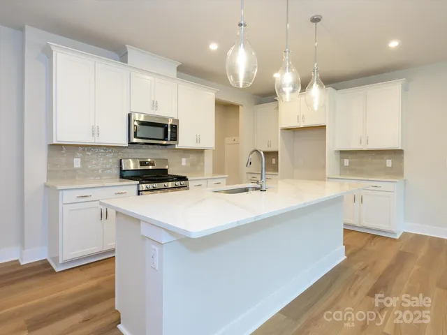 a kitchen with stainless steel appliances a sink a stove a microwave a center island and cabinets