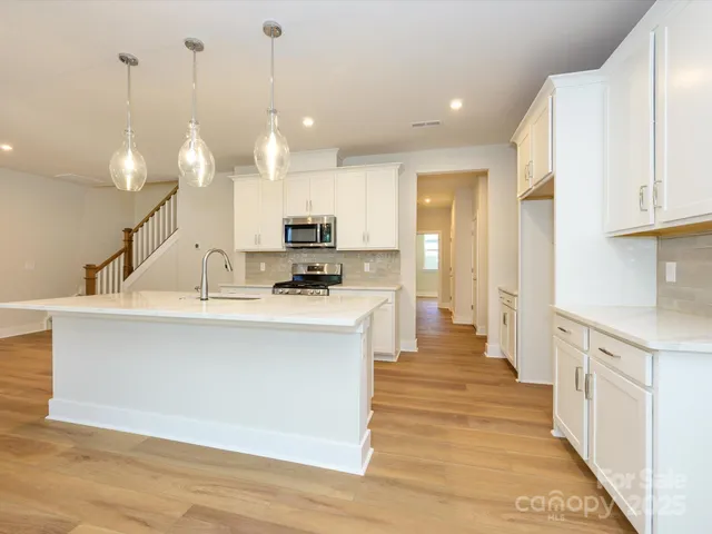 a view of a kitchen with kitchen island a sink stainless steel appliances and cabinets