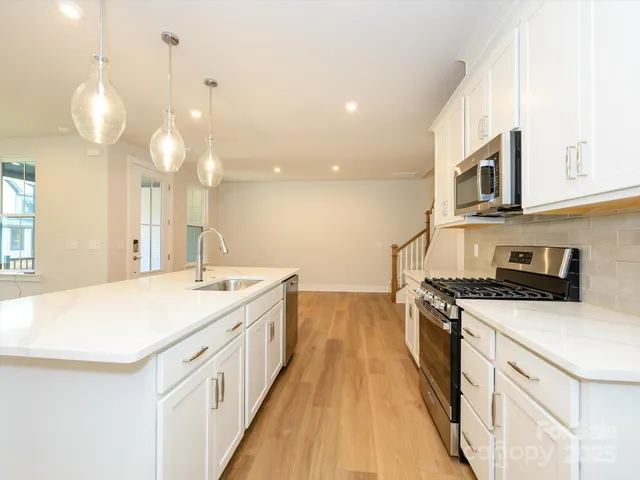 an open kitchen with a sink and wooden floor