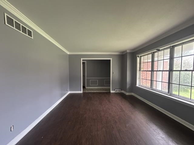 Spacious interior featuring dark wood-finish flooring, light gray walls, and white crown molding