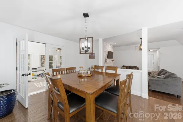 a view of a dining room and livingroom with furniture wooden floor a rug and a chandelier