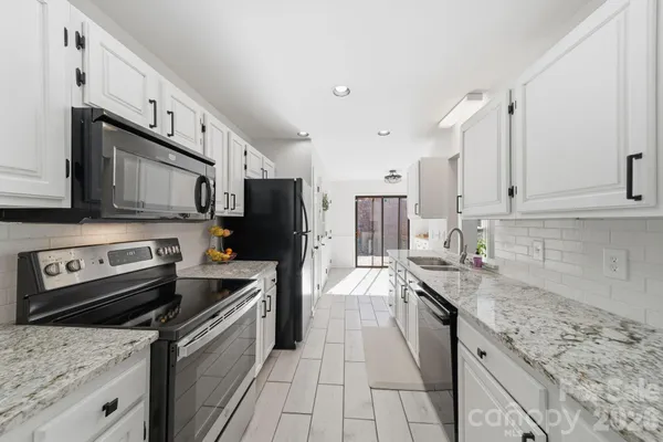 a kitchen with stainless steel appliances granite countertop a sink stove microwave and refrigerator