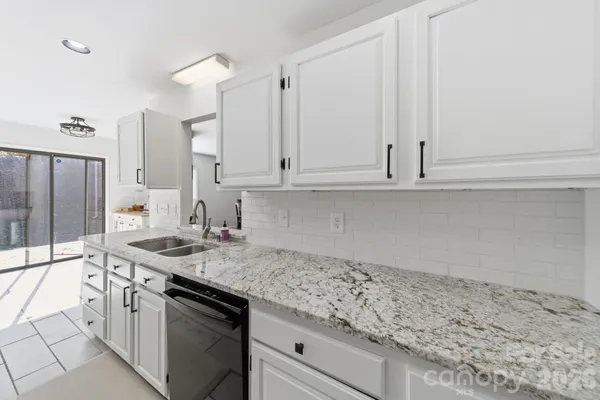 a kitchen with granite countertop white cabinets and a sink
