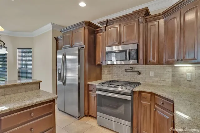 a kitchen with granite countertop a refrigerator stove and microwave