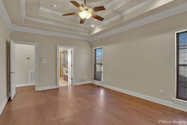 an empty room with wooden floor fan and windows