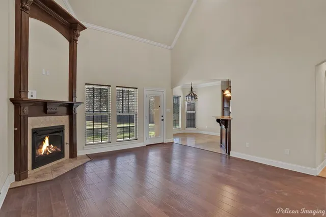 a view of an empty room with wooden floor fireplace and a window