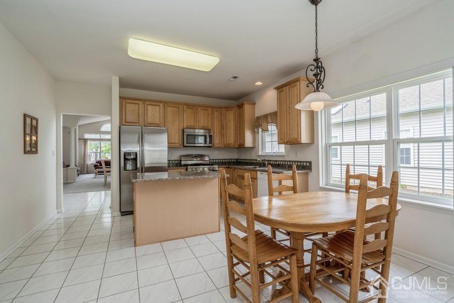 111 San Marco Road Monroe Township, NJ 08831 - Photo 9 of 31 a open kitchen with stainless steel appliances granite countertop a stove a refrigerator a sink a dining table and chairs with wooden floor