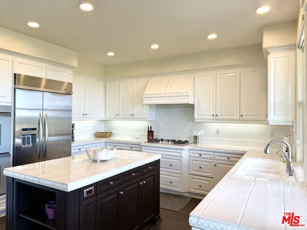 a kitchen with a sink a stove a refrigerator and white cabinets