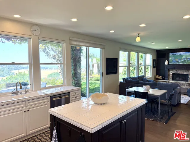 a kitchen with a stove a sink dishwasher a dining table and chairs with wooden floor